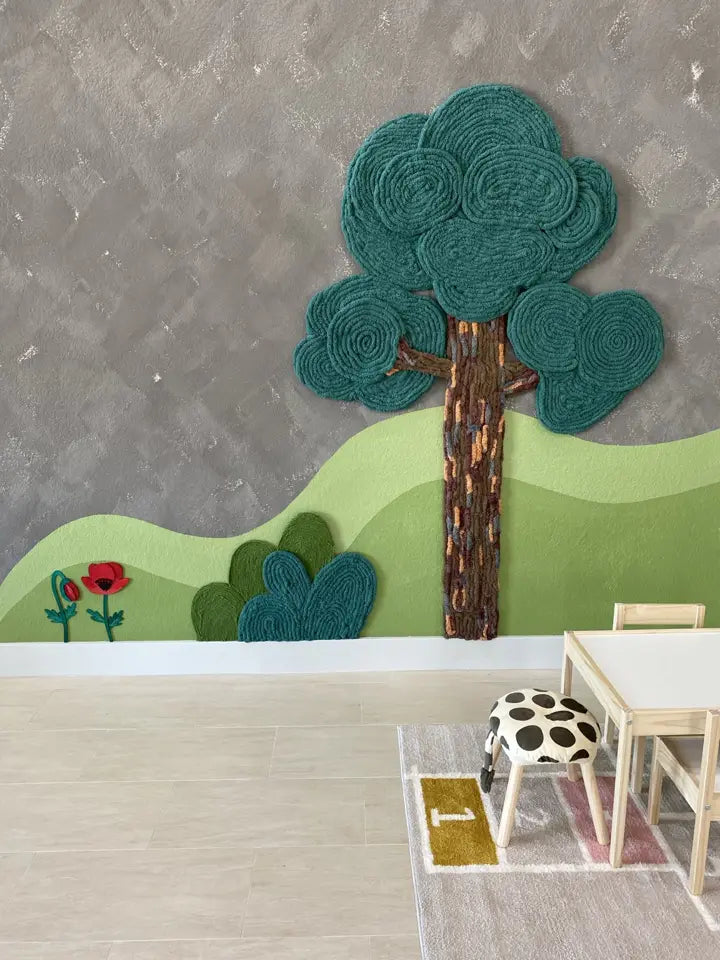 Dimensional yarn tree and painted green hills beside child-sized seating in the Pinnacle Montessori school lobby in Georgetown, Texas.