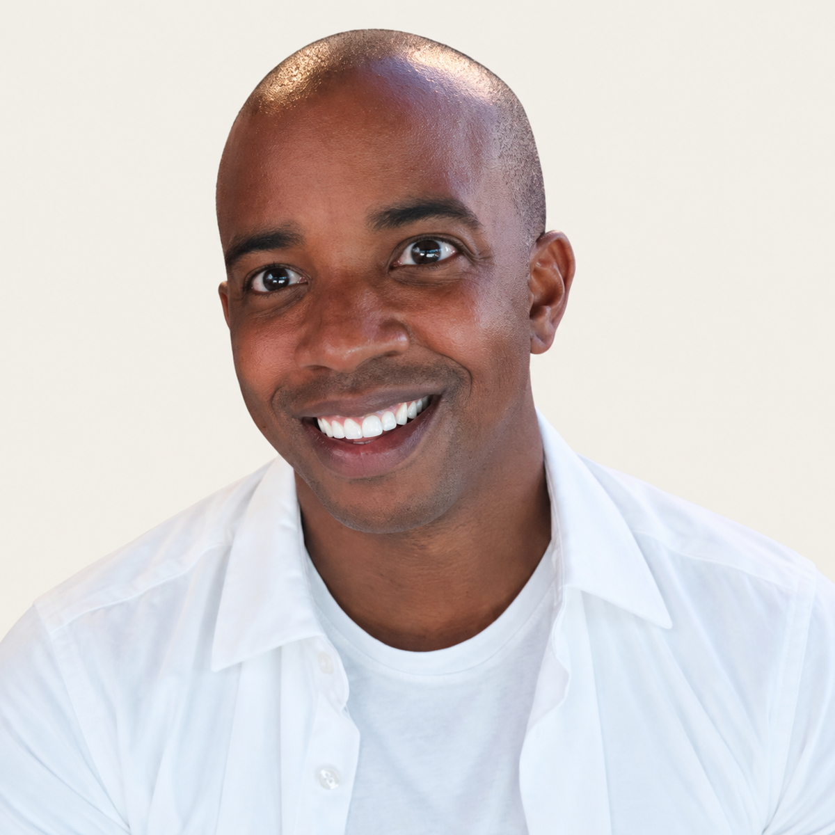 Kyle smiling in a white shirt against a warm beige background for the That Playful Life family portrait collection.
